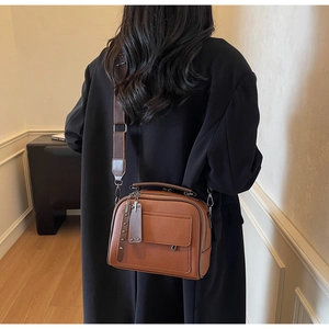 Rear view of model wearing a vintage brown leather crossbody bag with wide strap