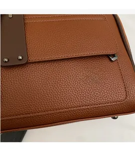 Close-up of brown litchi pattern leather texture with decorative metal rivet buckle detail