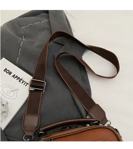Detail of brown litchi grain leather crossbody bag with wide adjustable canvas strap