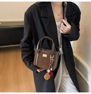 Detail of a brown suede bucket bag with gold hardware and creative fuzzy ball charms