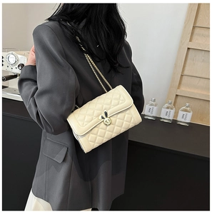 Close-up of beige quilted chain bag featuring a unique black and white rabbit ear clasp