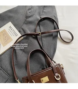 Detail of a brown leather bucket bag with an adjustable strap on a minimalist background