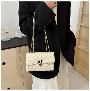 Detail of a beige quilted chain bag featuring a gold rabbit-shaped metal buckle and strap