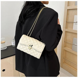 Detail of quilted beige leather bag featuring a gold bunny ear twist lock and metal chain
