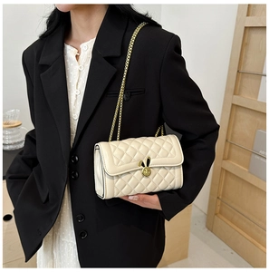 Close-up of beige quilted bag featuring a golden bunny ear lock and metal chain strap