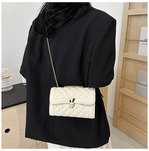 Quilted beige shoulder bag with a gold rabbit buckle and chain strap shown on a person