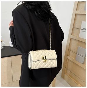 Close-up of beige quilted crossbody bag with gold rabbit lock on a black suit blazer