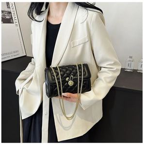 Detail of black quilted leather bag featuring a gold rabbit clasp and metal chain strap