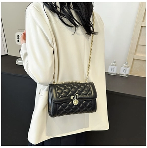 Detail of elegant black quilted crossbody bag featuring a unique golden rabbit metal clasp