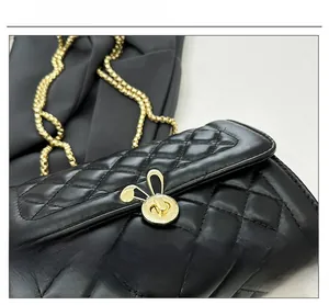Close-up of golden rabbit rotating lock on black quilted leather crossbody bag