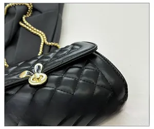 Detail of black quilted leather bag with gold rabbit ear lock and fine stitching