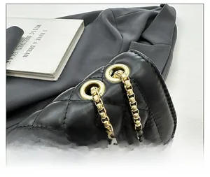 Detail of black quilted leather shoulder bag with gold chain and metal grommets