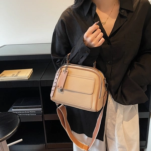 Beige lychee-grain small square bag with wide shoulder strap worn as a crossbody bag