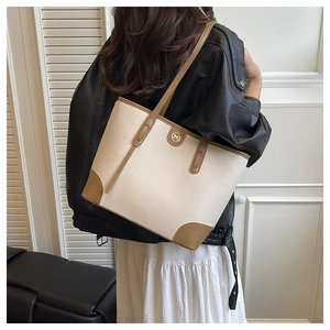Detail of minimalist beige faux leather tote bag with brown trim and gold logo