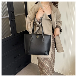 Detail of black pebbled leather tote bag with gold M logo and reinforced corner design