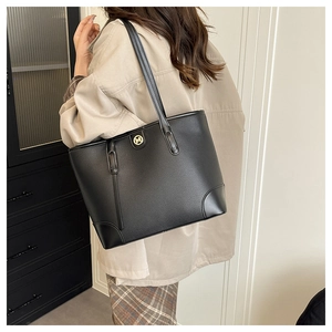 Detailed view of black pebbled leather tote bag with a golden M logo and long shoulder straps