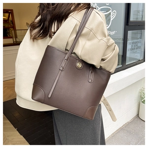 Detail of dark brown tote bag with gold M logo and pebbled texture for shoulder wear