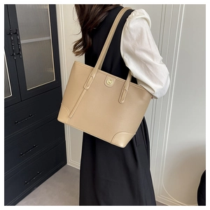 Close-up of khaki tote bag with lychee grain texture and gold logo on leather shoulder straps