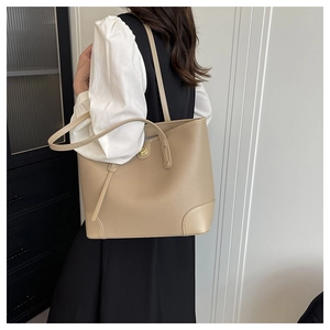 Close-up of beige leather tote bag with reinforced corners and golden magnetic buckle