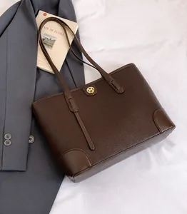 Detail of a dark brown pebble leather tote bag featuring a gold round metallic M logo