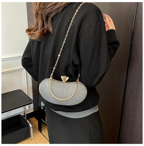 Silver sequin evening clutch bag with gold chain strap shown on a model's shoulder