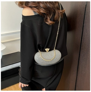Detail of silver glitter evening bag featuring round gold handles and chain strap