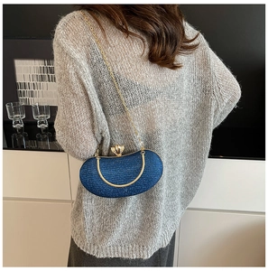 Detail of navy blue sequin moon bag with crown clasp and gold chain strap on shoulder