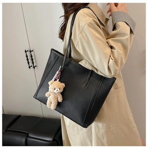 Close-up of black leather tote bag with pebble grain texture and cute brown bear charm