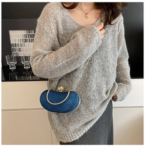 Detail of glittery navy evening bag with golden chain strap on gray sweater