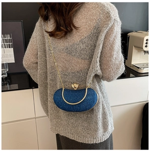 Detailed view of deep blue glitter evening clutch bag with gold shell clasp on a chain