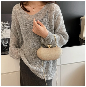 Detail of gold glitter evening clutch bag with metal handle and chain shoulder strap