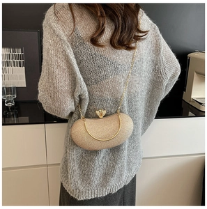 Detail of champagne gold evening bag with mesh texture, metal handle and chain strap