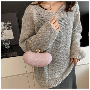 Close-up of pink glitter evening bag with gold handle and chain on a stylish model