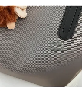 Détail du tissu rayé du sac fourre-tout avec poignée en cuir noir et breloque singe