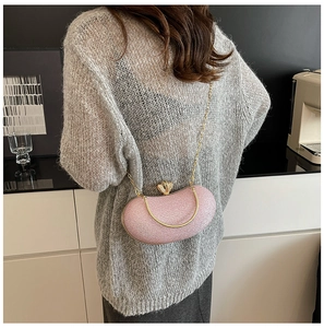 Detail of pink glitter evening bag with gold circular handle and delicate chain strap