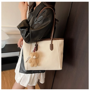 Detail of vintage beige and brown tote bag featuring teddy bear charm and pebble leather texture