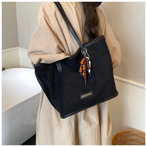 Détail du sac cabas en daim noir avec breloque en perles colorées et logo doré
