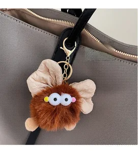 Détail d'un charme de sac monstre en peluche marron avec des ailes et de gros yeux