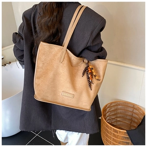 Détail du sac cabas en daim kaki avec perles en bois et étiquette de marque