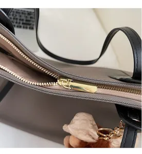 Gros plan du zip doré sur le cabas en nylon kaki avec son charm ours en peluche marron