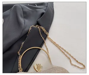 Detail of the glittering gold evening bag with a crown clasp and metal chain strap