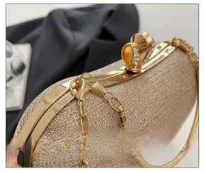Close-up of champagne gold glitter clutch with rhinestone clasp and gold chain detail