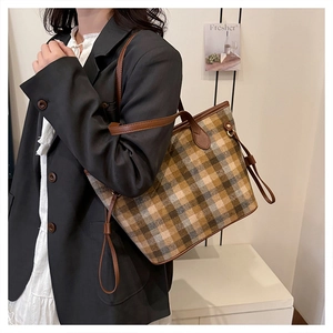 Detail van een grote geruite wollen shopper met bruine leren schouderbanden op een model