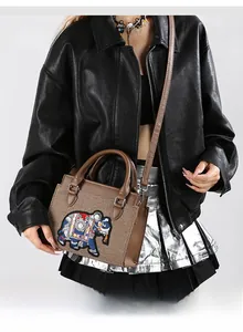 Détail de la broderie d'éléphant sur le petit sac carré tissé marron en bandoulière