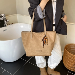 Sac cabas en daim marron avec pendentif en perles de bois dans un décor de style de vie