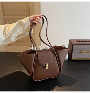 Dettaglio della borsa tote in pelle marrone con ali pieghevoli e chiusura in metallo oro