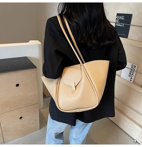 Dettaglio borsa tote beige con struttura piegata e fibbia in metallo dorato sulla spalla