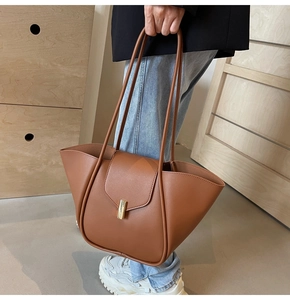 Dettaglio borsa tote in pelle caramello con fibbia dorata e sottili spalline in pelle
