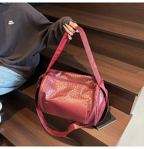 Detail of burgundy woven tote bag with smooth leather patch and metal rivets decoration