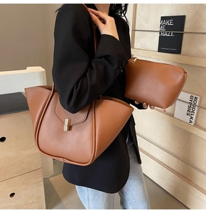 Dettaglio della borsa tote in pelle marrone con design alato e fibbia dorata lucida